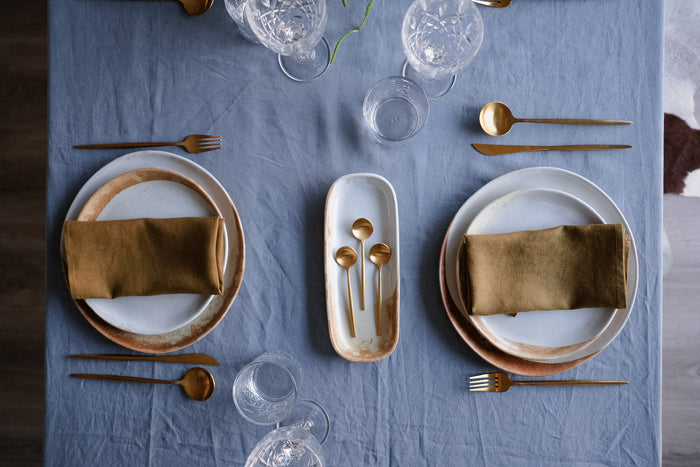 Birds Eye view of a table setting with a blue linen table cloth, and handmade ceramic dinner plates by Palinopsia Ceramics