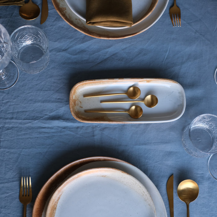Bird's eye-view of a rectangle dish with gold cutlery for entrees by Palinopsia Ceramics