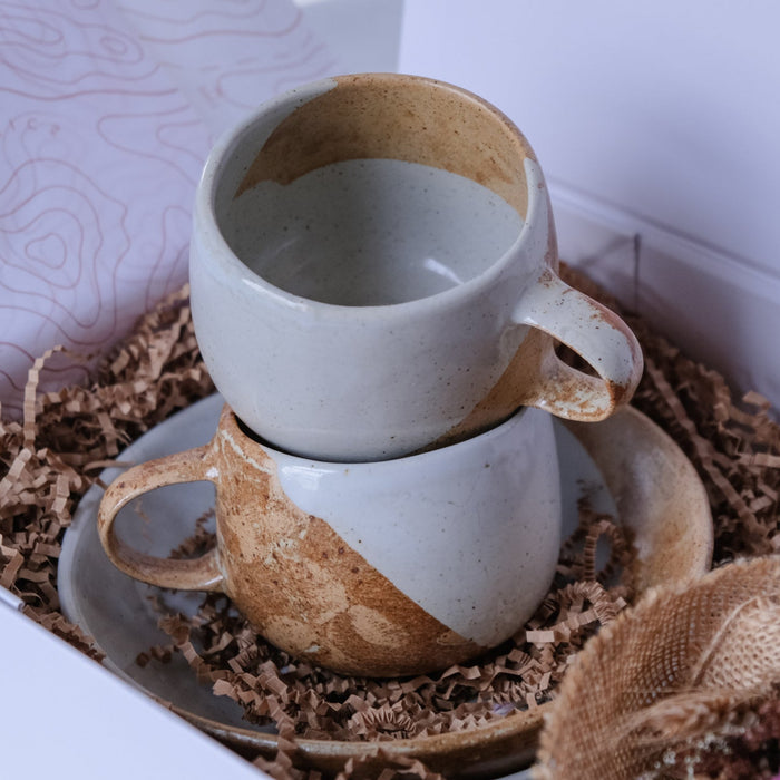 Two ceramic mugs stacked on a bowl and packed in a gift box