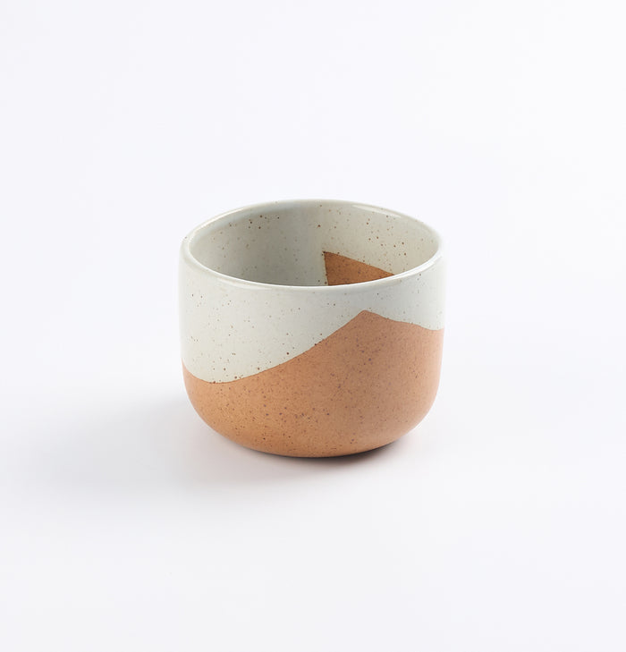 Ceramic stoneware cup with two-tone blue and brown design on a white background