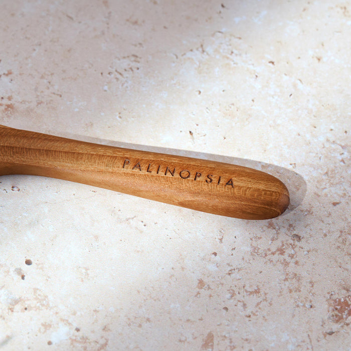 Close-up shot of the handle of a teak wooden spreading knife with a Palinopsia label on the handle.