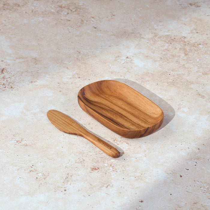 Palinopsia teak wooden serving tray and knife on a light stone background.