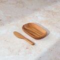 Palinopsia teak wooden serving tray and knife on a light stone background.