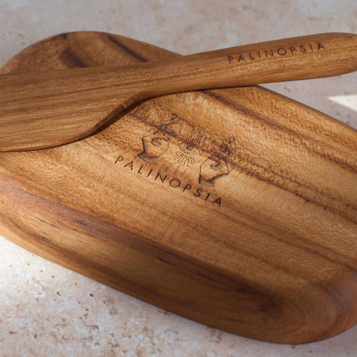 Detailed shot of a small teak wooden tray and knife with the Palinopsia logo on the bottom.