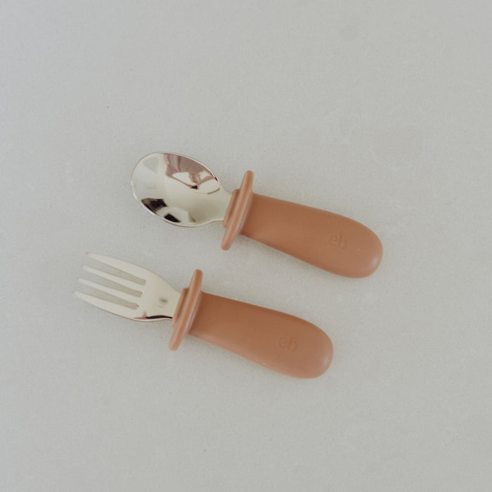 Set of children's fork and spoon with brown handles on a light gray background