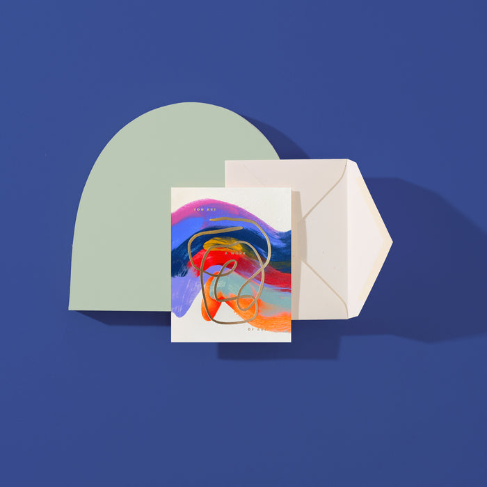 You Are A Work Of Art handmade artisanal greeting card with blue, orange and yellow paint swirls and an envelope on a blue background.